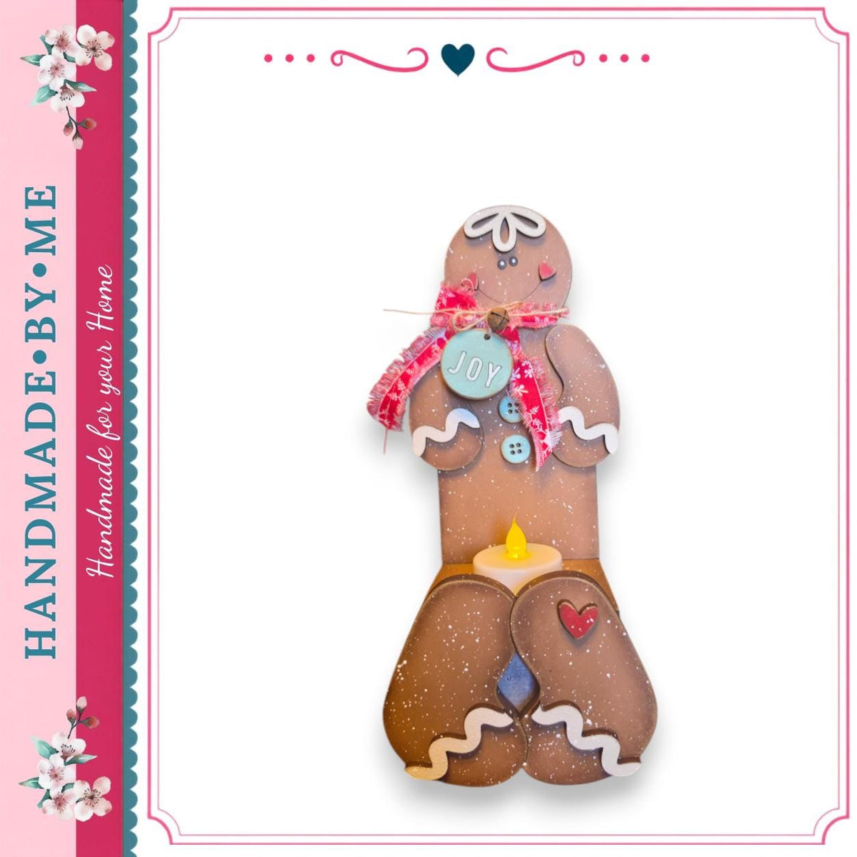 A handcrafted gingerbread man figure with a blue tag that says "Joy" and a red bow around its neck.