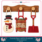 a wooden snowman, a wooden sled with the word "Hello Winter" written on it, and a red shovel, all hanging on a wooden board.