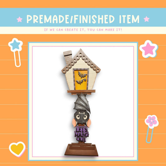 a Halloween-themed decoration, including a bat-shaped house and a bat-shaped sign with the phrase "Let's have some fun".