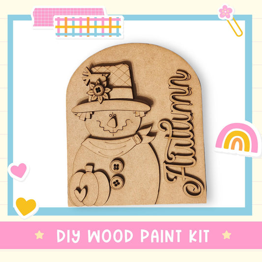 A DIY wood paint kit featuring a wooden scarecrow with a hat and a pumpkin, surrounded by colorful stickers and a rainbow.