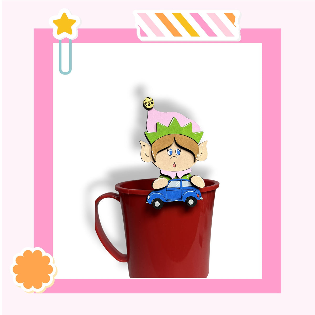 A cartoon elf figurine is sitting inside a red mug, with a toy car attached to the mug.