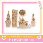 a DIY wood paint kit with various wooden shapes and decorations, including a Santa Claus sign, a snowman, and a Christmas tree.