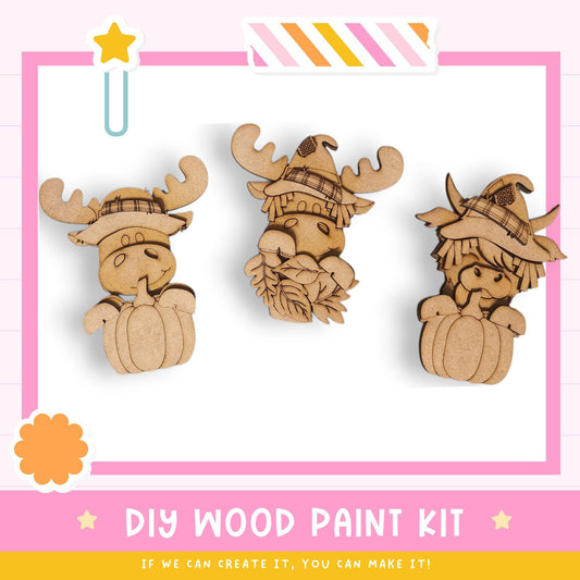 three wooden animal figurines wearing hats, likely representing moose or deer, set against a pink and white background.