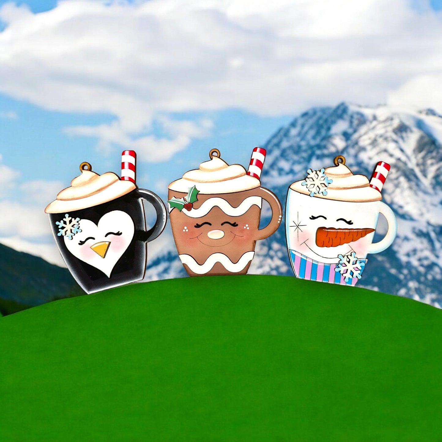 a group of three coffee mugs sitting on top of a green hill