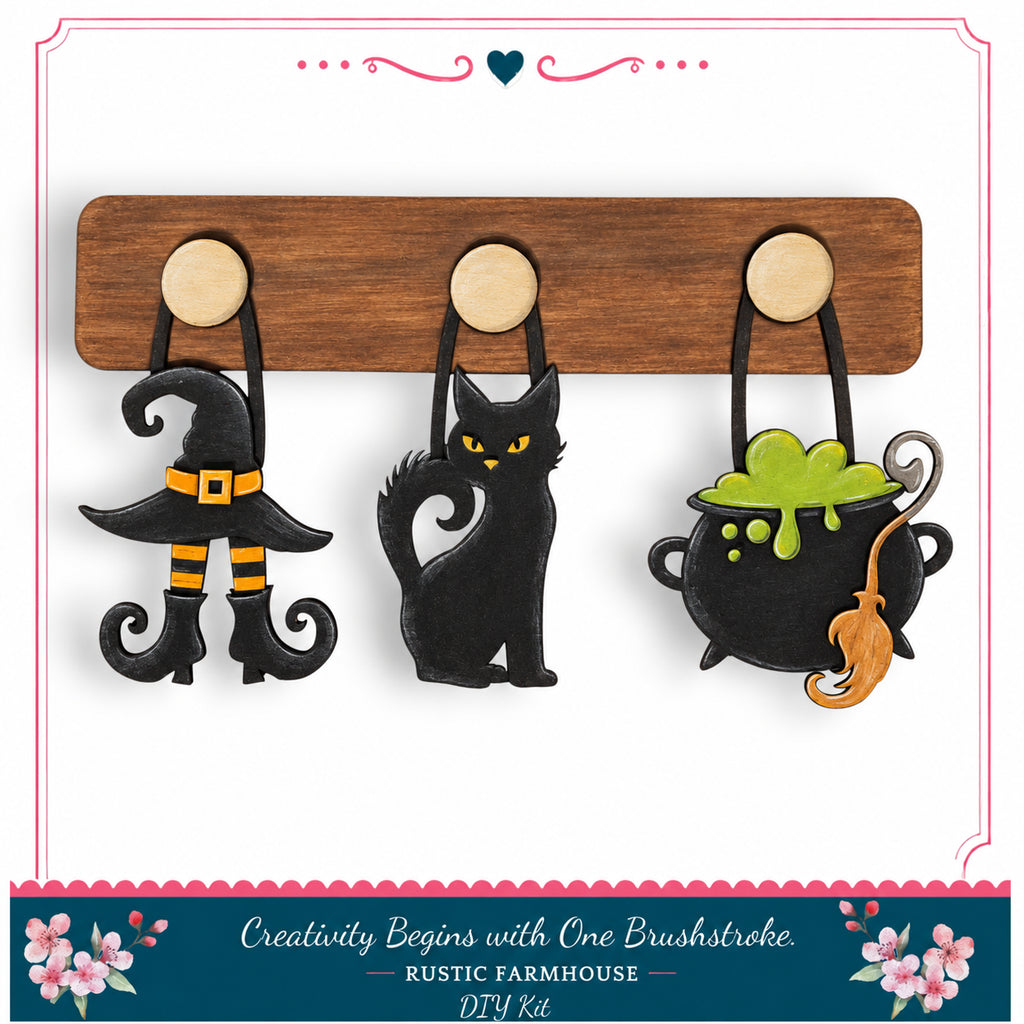 A DIY kit featuring a wooden board with three Halloween-themed charms hanging from it, including a witch's hat, a black cat, and a cauldron with a green substance.