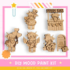 The image is a DIY wood paint kit featuring various wooden characters, including a knight, a princess, and a unicorn, along with a sign that says "UWDER YOURS".