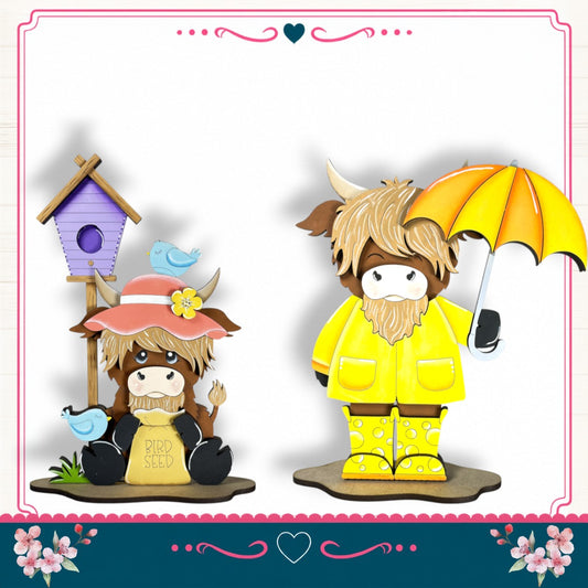 two cartoon cow figurines, one wearing a pink hat and the other wearing a yellow raincoat and yellow boots, standing next to each other and holding an umbrella.