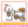 a DIY wood paint kit, including a wooden cart with carrots and flowers, and a wooden bunny figure holding a sign that says "HOP THIS WAY".