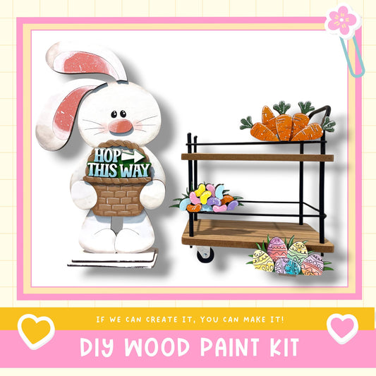 a DIY wood paint kit, including a wooden cart with carrots and flowers, and a wooden bunny figure holding a sign that says "HOP THIS WAY".