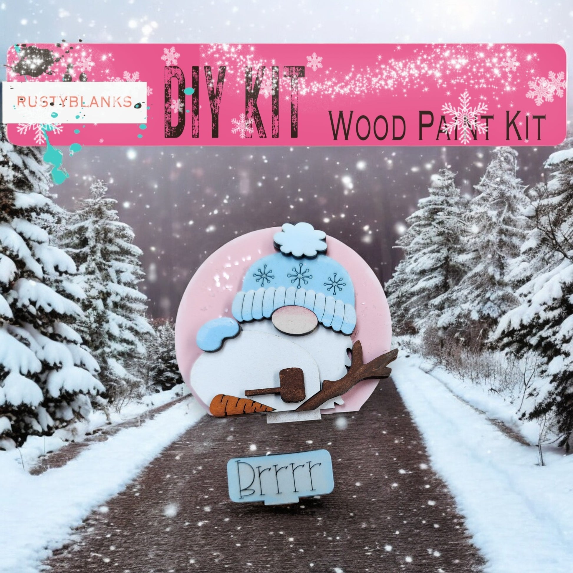 A DIY wood paint kit for creating a snowman, featuring a pink snowman figure and a snowman-themed sign. The background shows a snowy landscape with pine trees.