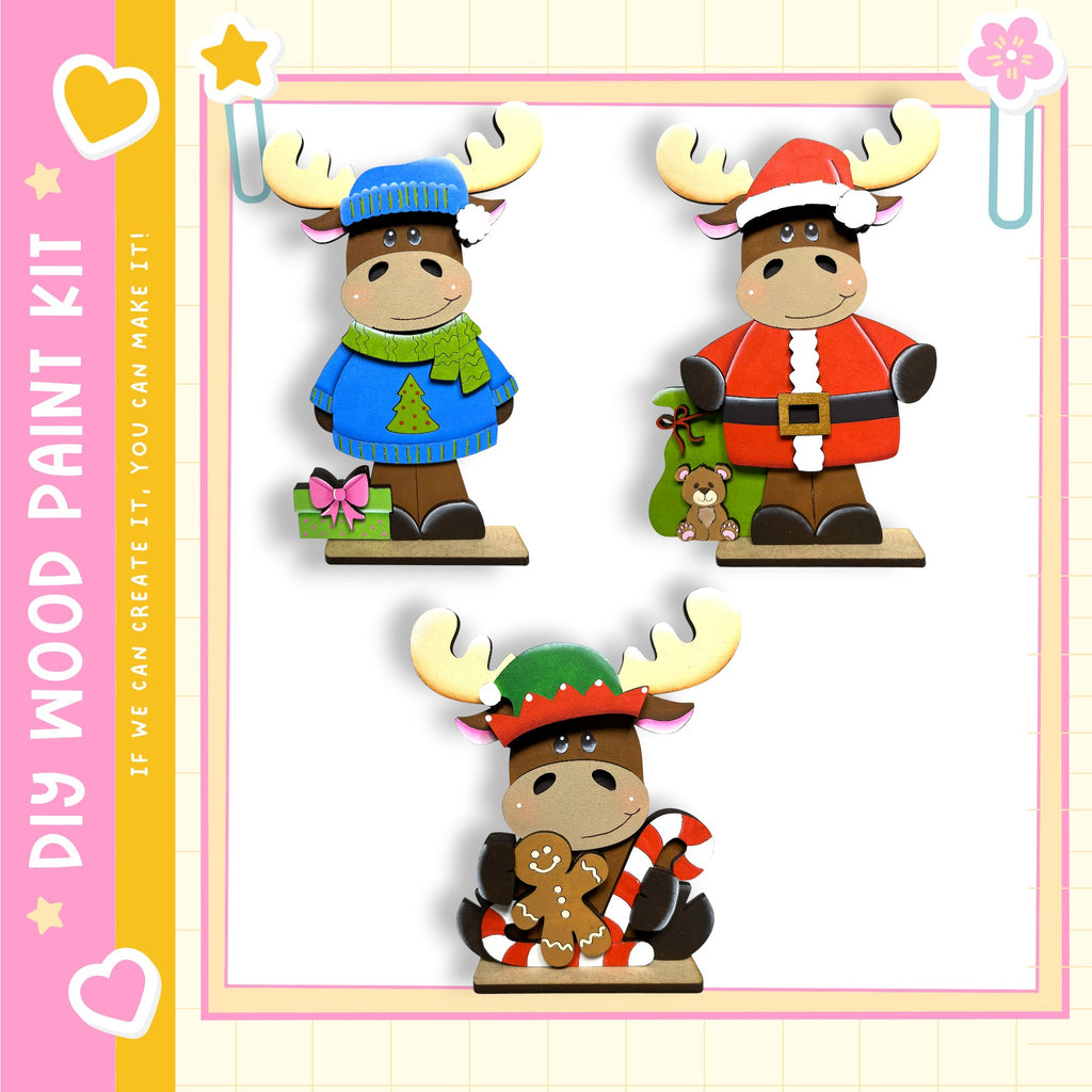 three wooden figurines of moose wearing different outfits, including a blue sweater, a Santa Claus outfit, and a green sweater.