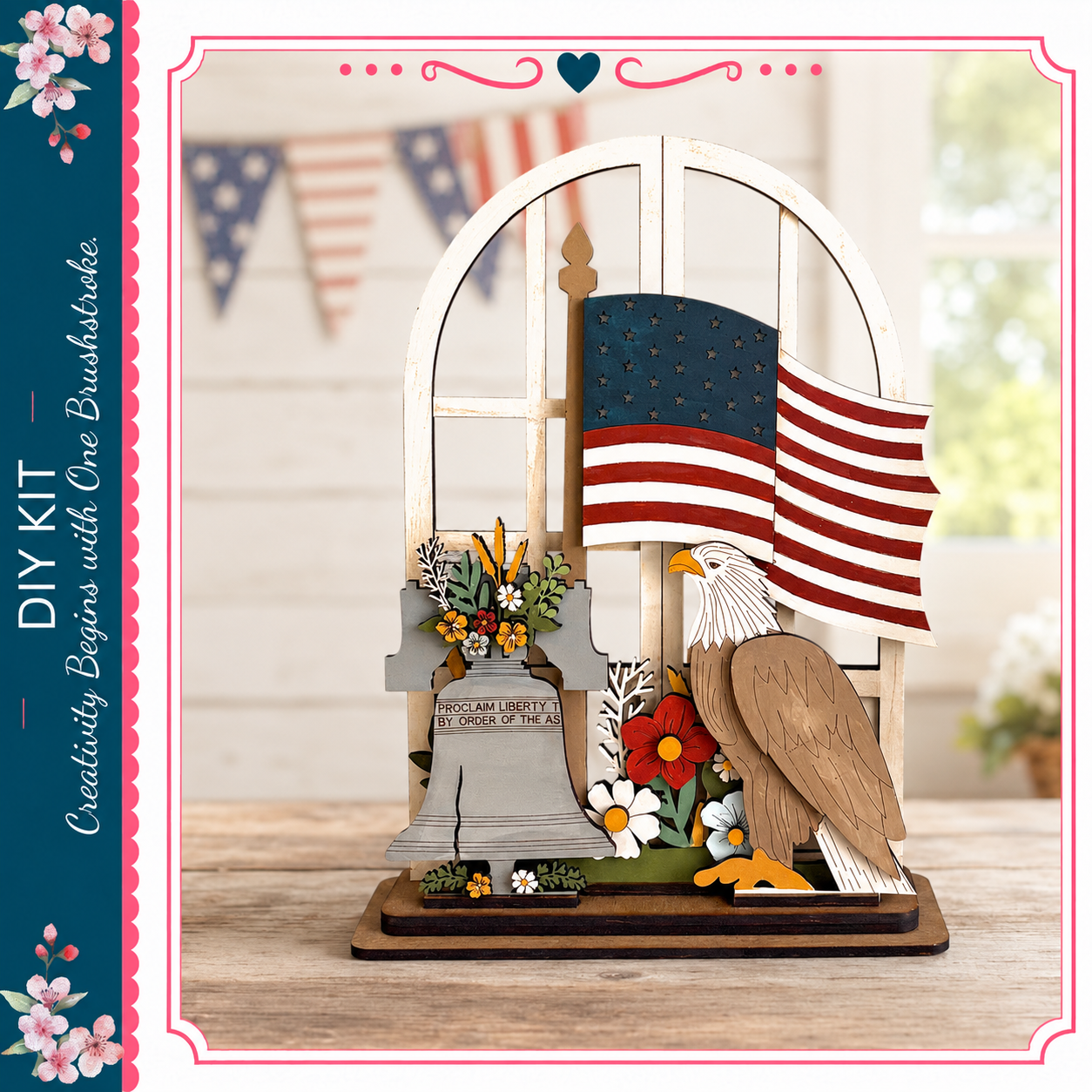 A wooden American flag-themed display featuring a wooden eagle, a wooden bell, and flowers, with a blurred background of American flags and a window.