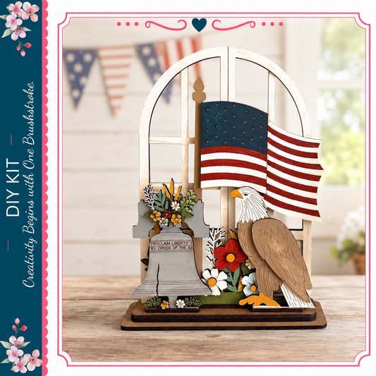 A wooden American flag-themed display featuring a wooden eagle, a wooden bell, and flowers, with a blurred background of American flags and a window.