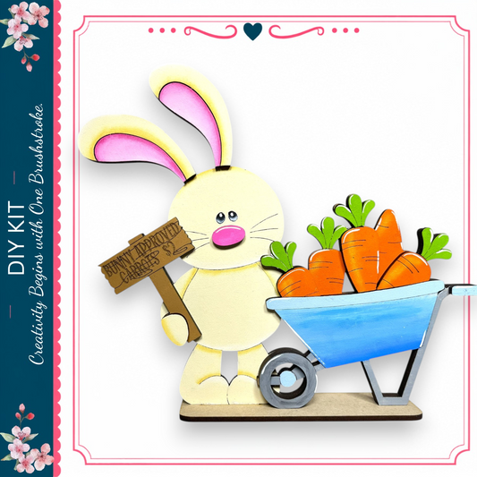 A wooden bunny holding a sign that says "Bunny approved carrots" next to a blue wheelbarrow filled with orange carrots.