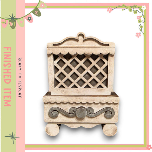a wooden cabinet with a lattice design on the front, set against a pink and green floral border.