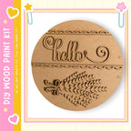 a wooden paint kit with a round wooden plaque that has the word "Hello" carved into it. The plaque also has a decorative design on it.