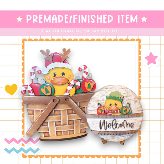 a basket with a duck wearing a Santa hat, and a wooden sign with the word "Welcome" on it.