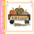 A wooden wagon with carved pumpkins and a sign that says "fall harvest" is displayed against a pink and yellow background.