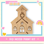 a DIY wood paint kit for creating a wooden church-like structure, with a heart and a rainbow-colored sticker on the right side.