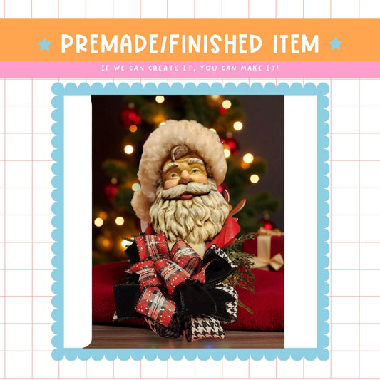 a close-up of a Santa Claus figurine, with a blurred background of a Christmas tree and other holiday decorations.