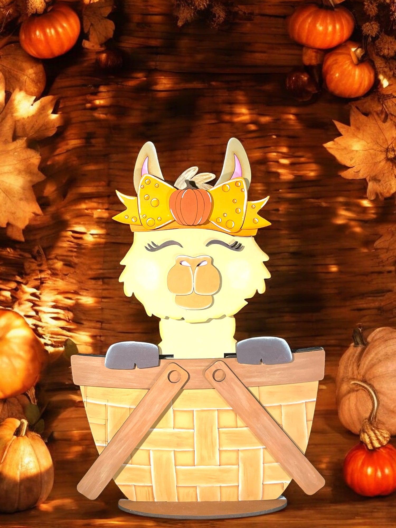 a paper cut out of a llama in a basket surrounded by pumpkins