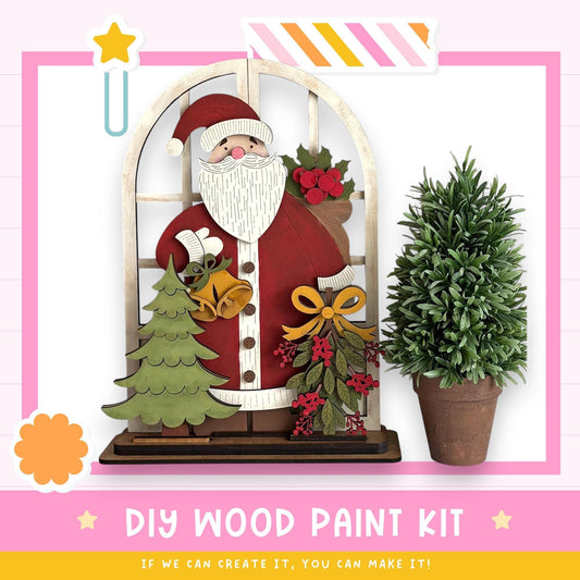 a DIY wood paint kit for creating a wooden Santa Claus figure, with a potted plant and a star decoration.