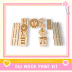 a DIY wood paint kit with various wooden shapes and designs, including a heart-shaped piece, a wreath-shaped piece, and a heart-shaped piece. The kit appears to be made of wood and is displayed against a white background.