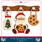 A wooden shelf with three wooden ornaments hanging on it, including a Christmas tree ornament, a cookie-shaped ornament, and a cookie-shaped ornament. Santa Claus is depicted holding a cookie in his hand.