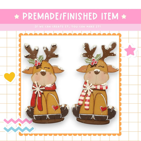 two wooden reindeer figurines, each wearing a red scarf and antlers, sitting on a white background.