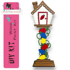 a wooden birdhouse with a red door and a pink banner