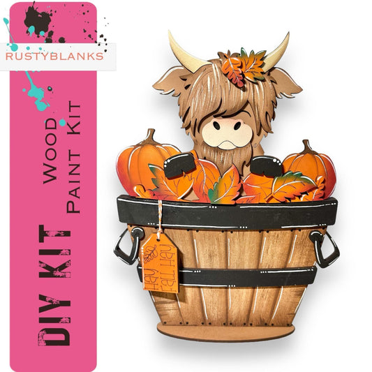 a wooden cutout of a cow in a basket of pumpkins