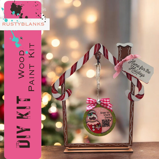 a wooden house ornament with a pink ribbon